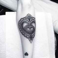 a black and white photo of a heart with an eye tattoo on the leg,