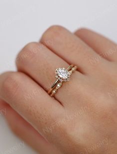 a woman's hand wearing a gold ring with a white diamond on the side