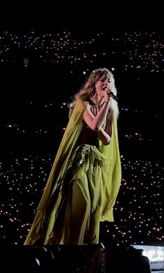 a woman in a green dress singing on stage