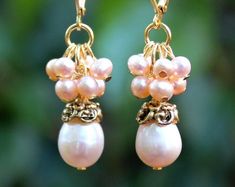 "This lovely pair of earrings features a luminous champagne freshwater pearl, which are accented with an ornate pewter bead cap, plated in 24 karat gold. This striking color combination is offset with beautiful clusters of champagne freshwater pearls. Hanging from a surgical steel lever-back, it measures 1 ¼\" in length. Pearls are known to symbolize purity of heart & mind. Pearls stimulate spiritual transformation, wisdom, integrity and pure love. They bring out the best qualities that rest wit Pink Pearl Charm Wedding Earrings, Pink Pearl Charm Earrings For Wedding, Pink Pearl Earrings For Wedding, Elegant Pink Pearl Earrings For Celebration, Nickel-free Pearl Earrings For Weddings, Nickel-free Gold Pearl Earrings For Wedding, Pearl Cluster Earrings, Hematite Crystal, Spiritual Transformation