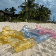 several inflatable objects are laying on the sand at the beach near palm trees