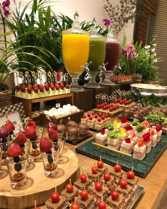 an assortment of desserts and drinks on display at a buffet table with flowers in the background