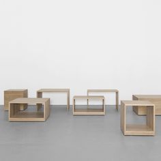 four wooden tables sitting on top of a cement floor next to each other in front of a white wall