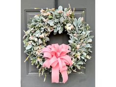 a wreath with pink bow hanging on the front door