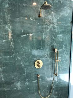 a shower head and hand shower in a bathroom with green marbled wall behind it