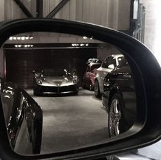 two cars are seen in the rear view mirror of a car parked in a garage