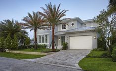 a house with palm trees in front of it and a driveway leading to the garage