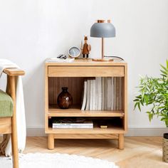 a small wooden shelf with books on it next to a chair and potted plant