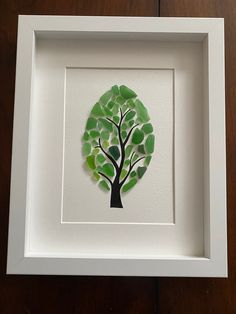 a white frame holding a green tree cut out of paper