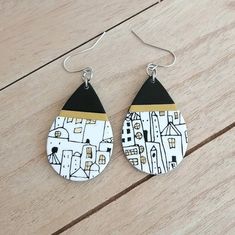 pair of earrings with black and white designs on wooden table next to wood plank floor