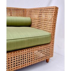 a wicker couch with green cushions on it's back and side panels,