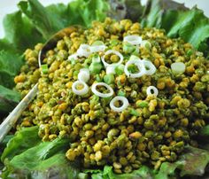 a bowl filled with lettuce and onions on top of a table