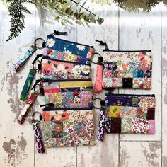 several small purses are lined up on a wooden surface with flowers and leaves in the background