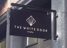 the white door studio sign hanging from the side of a building