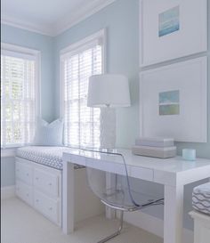 a white desk and chair in a room with blue walls, windows and pictures on the wall