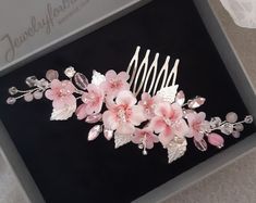 a hair comb with pink flowers and leaves on it, in a black gift box