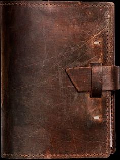 an old brown leather journal with writing on the front and back cover that has been stitched together