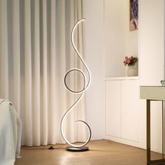 a white lamp sitting on top of a wooden floor next to a mirror and table