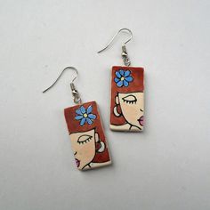 "Unique handmade earrings featuring a runette girl. These earrings are distinctive and fun to wear. You can pair them with any outfit, be it casual, everyday or special occasions.  The girl earrings are crafted using polymer clay and a technique called Nambi. They are cured to ensure optimum color and strength and then hand-sanded, colored, and glazed. The front side of each earring features a drawing made by hand in clay. The motif on each earring is unique, similar but not identical. The back of the earrings is made of dark-colored clay and textured. Dimension: about 3 × 1,5 cm/ 1.18 × 0.6 inches   Total length of earrings (including ear wires) is 5 cm/ 1.80 inches. The earrings are already made and ready for shipping. They will be delivered in a lovely box and bubble wrap envelope. \".. Adjustable Earrings As Gift For Her, Unique Hand Painted Earrings For Everyday, Unique Hand Painted Earrings For Everyday Wear, Unique Hand Painted Everyday Earrings, Unique Red Flower Earrings, Artistic Dangle Flower Earrings For Gifts, Artistic Dangle Flower Earrings As Gift, Whimsical Handmade Earrings For Everyday, Handmade Cute Plug Earrings For Gift