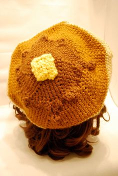 a knitted hat with a yellow flower on the top is shown in close up