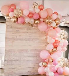 a bunch of balloons that are hanging from the ceiling in front of a wooden wall