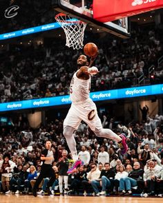 a man dunking a basketball in front of a crowd