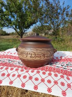 a brown bowl sitting on top of a red and white table cloth next to a tree