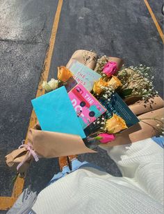 a bouquet of flowers is wrapped in brown paper and sitting on the side of the road