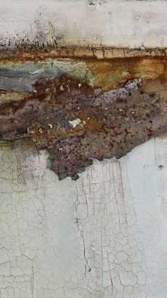 an old rusted piece of metal on the side of a building with peeling paint