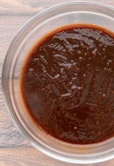 a glass bowl filled with sauce on top of a wooden table