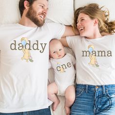 a man and woman laying on top of a bed next to a baby wearing matching shirts