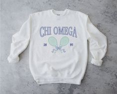 chi o is always the perfect match <3 ♡ Super soft sweatshirt comes in unisex sizing! Reference the size chart for additional details. It is recommended to SIZE UP for an oversized fit   ♡ Sweatshirt comes in white with a navy, blue and green print. Please check listing photos for color reference! ♡ Please make sure you are ordering for the correct sorority before placing an order! This listing is for CHI OMEGA. We are unable to accept returns or exchanges for this since all items are made to order.   ♡ INSTRUCTIONS FOR CARE:  1. Turn inside out before washing  2. Wash on a gentle cycle  3. Recommended not heat dry to prevent any minimal shrinking, hang to dry instead ♡ It is important that you LOVE your product! If you have any questions or concerns upon receiving your product, please cont Sorority Sweatshirt With Letter Print In Relaxed Fit, Cotton Sorority Sweatshirt With Graphic Print, Sorority Letter Print Sweatshirt In Relaxed Fit, Cotton Sweatshirt With Graphic Print For Sorority, Sorority Long Sleeve Graphic Sweatshirt, White Sorority Sweatshirt With Letter Print, Sorority Graphic Print Long Sleeve Sweatshirt, Aesthetic Greek, Tennis Sweatshirt