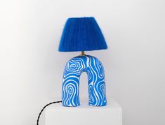 a blue lamp sitting on top of a white block