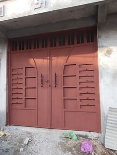 two red doors are open on the side of a building that's under construction