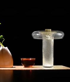 two vases sitting on top of a wooden table next to a bowl and plant