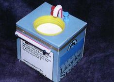 a blue box with a yellow and white bowl on it's lid sitting on a purple surface