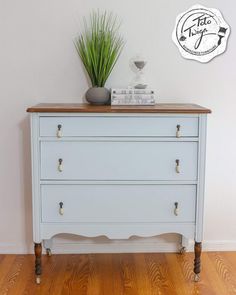 a white dresser sitting on top of a wooden floor next to a potted plant