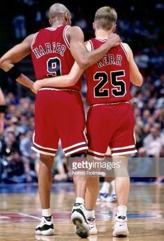 two basketball players standing on the court with their arms around each other