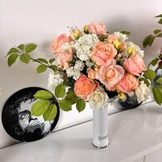 a vase filled with pink and white flowers on top of a table next to a mirror