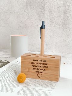 a wooden pen holder with writing on it and an orange ball sitting next to it