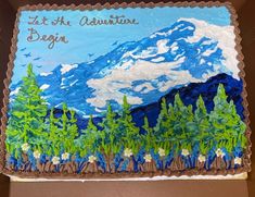 a decorated cake in the shape of a mountain with blue sky and clouds on it