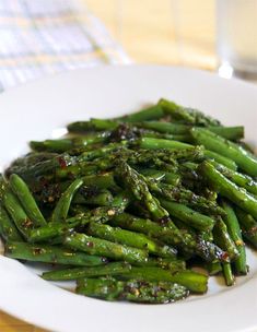 a white plate topped with asparagus covered in seasoning