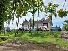 a large house sitting on top of a lush green field next to tall palm trees