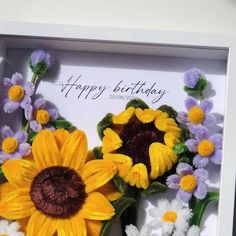 a birthday card with sunflowers and daisies in a white frame on a table