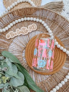 a glass jar sitting on top of a wicker tray next to some leaves and beads