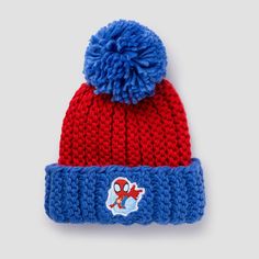 a red and blue knitted hat with spiderman on the front, sitting on a white surface