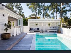 an outdoor pool with lounge chairs and table next to it