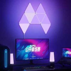 two computer monitors sitting on top of a desk next to a keyboard and mouse in front of a purple wall