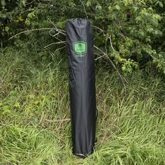 a black bag sitting on top of a lush green field next to tall grass and trees