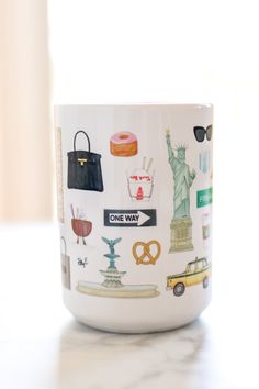 a coffee mug with the statue of liberty on it and other travel stickers all over it